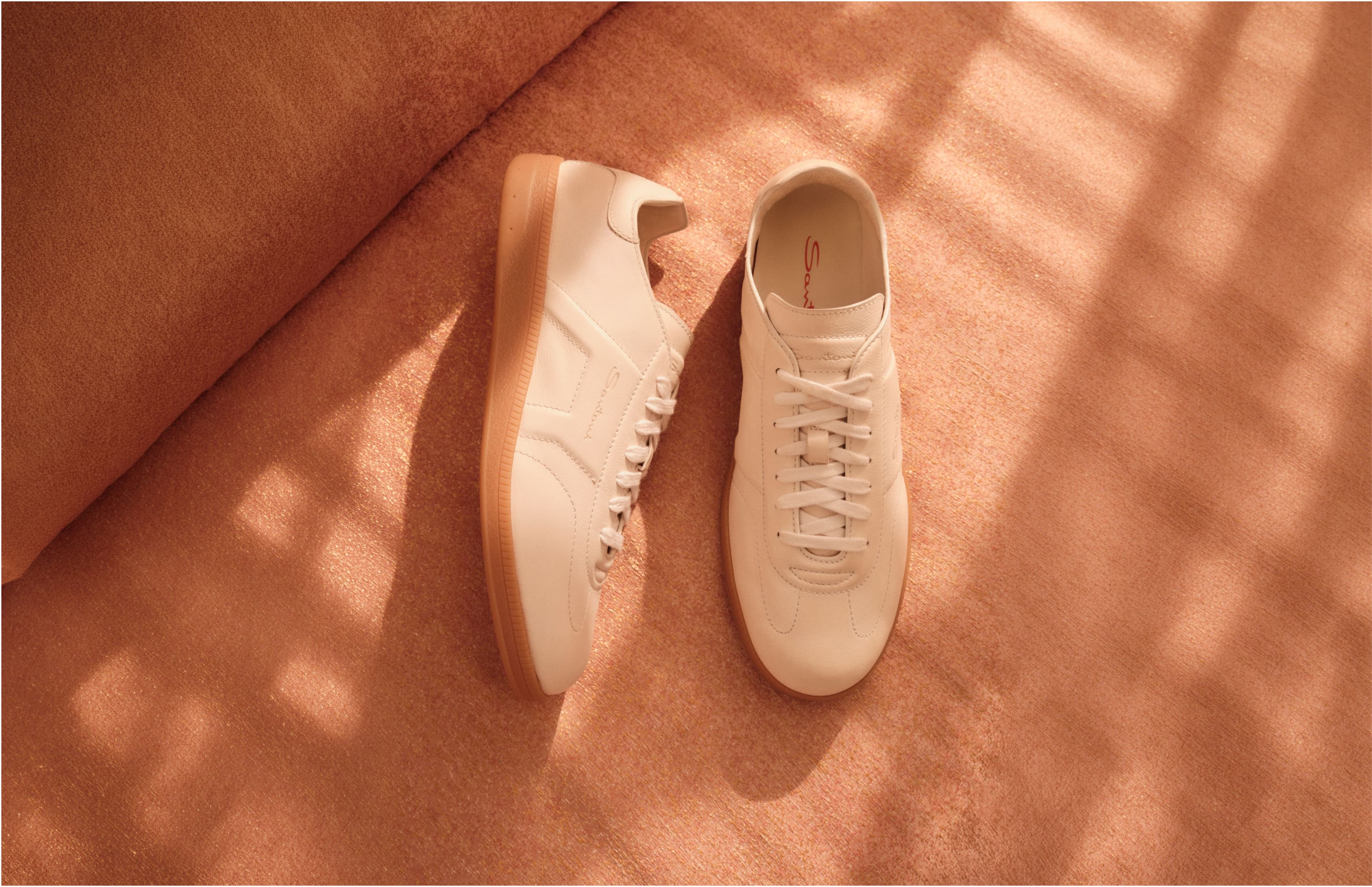 Shop trainers — cream leather sneakers in soft afternoon light.