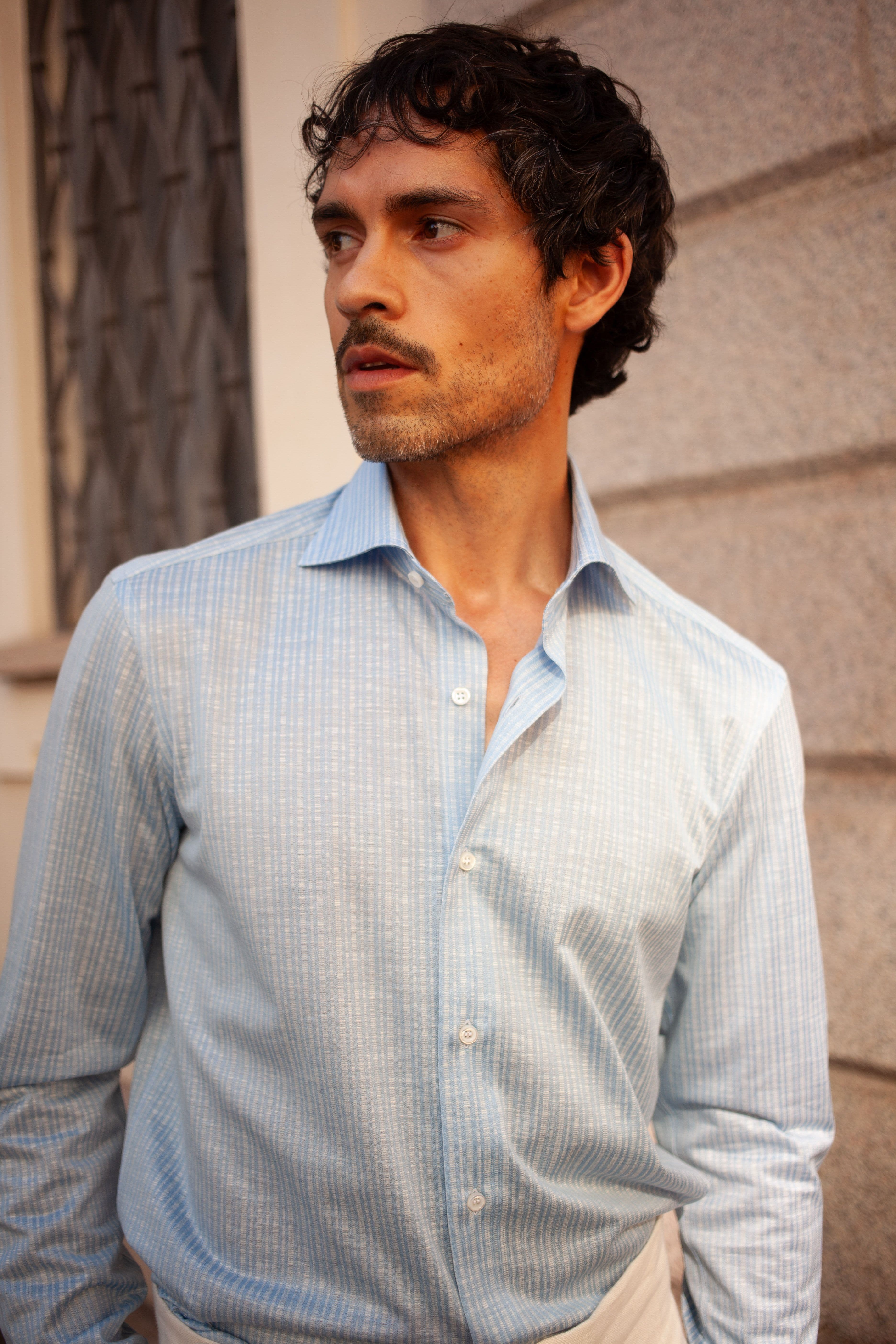 Man looking away from camera wearing blue Fray shirt.